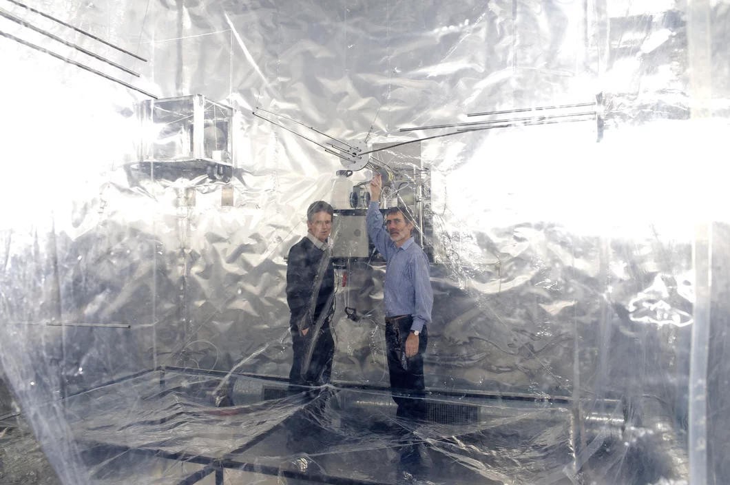 PSI-Forscher Urs Baltensperger (links) und Josef Dommen neben der Smogkammer, in der Vorgänge in der Atmosphäre simuliert werden (PSI/F. Reiser)