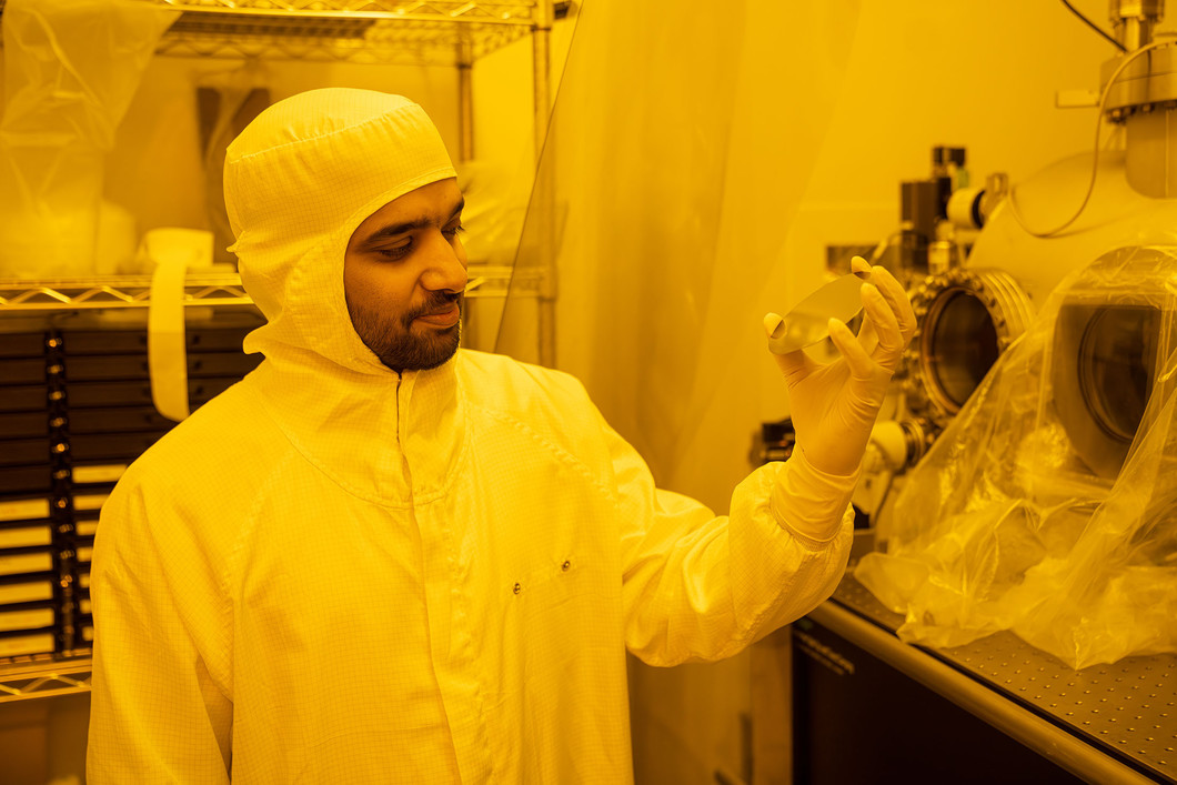 Prajith Karadan in the clean room looking at the reflective surface of a silicon wafer. 