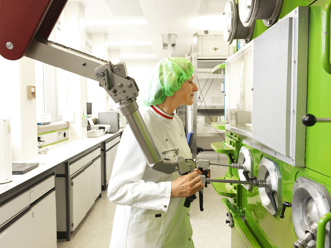 Eine PSI-Laborantin steuert mittels eines Manipulators die Abläufe im Inneren einer mit Blei abgeschirmten Kammer (Isolator), in der das radioaktive Medikament 90Y-Zevalin® hergestellt wird.(Quelle:PSI)