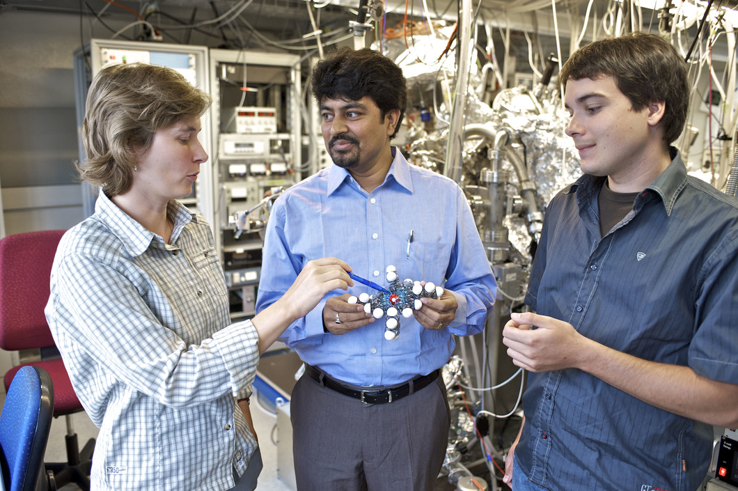 The PSI researchers Dorota Chylarecka, Nirmalya Ballav and Christian Wäckerlin discussung at the model of a  porphyrin molecule. (PSI/M. Fischer)