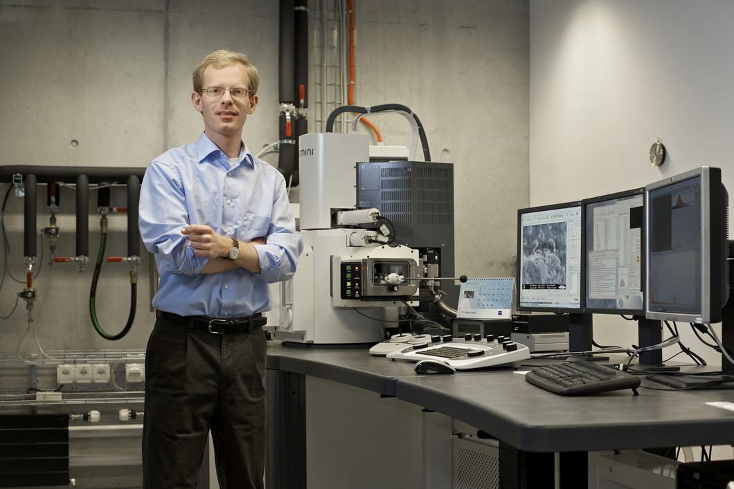 Preisträger Andreas Hintennach vom Paul Scherrer Institut neben seinem Arbeitsgerät, einem Rasterelektronenmikroskop.