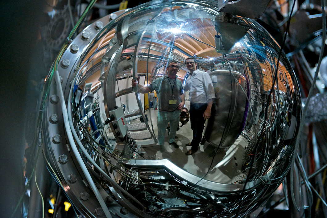 Die Forscher Milan Radovic und Nicolas Plumb spiegeln sich im Elektronendetektor der SIS-Strahllinie an der Synchrotron Lichtquelle Schweiz SLS des Paul Scherrer Instituts. (Foto: Paul Scherrer Institut / Markus Fischer)