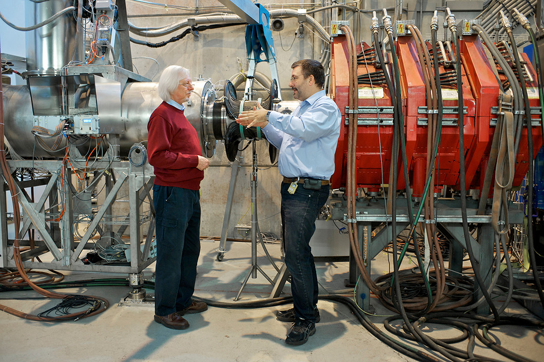 The steel pipe that conducts the muons to the experiment where Stefan Ritt and his colleagues search for a specific, extremely rare muon decay. The DRS4 microchip was developed for this experiment. The photo shows two of the PSI researchers involved: Peter-Raymond Kettle (left) and Stefan Ritt. (Photo: Paul Scherrer Institute/Markus Fischer)