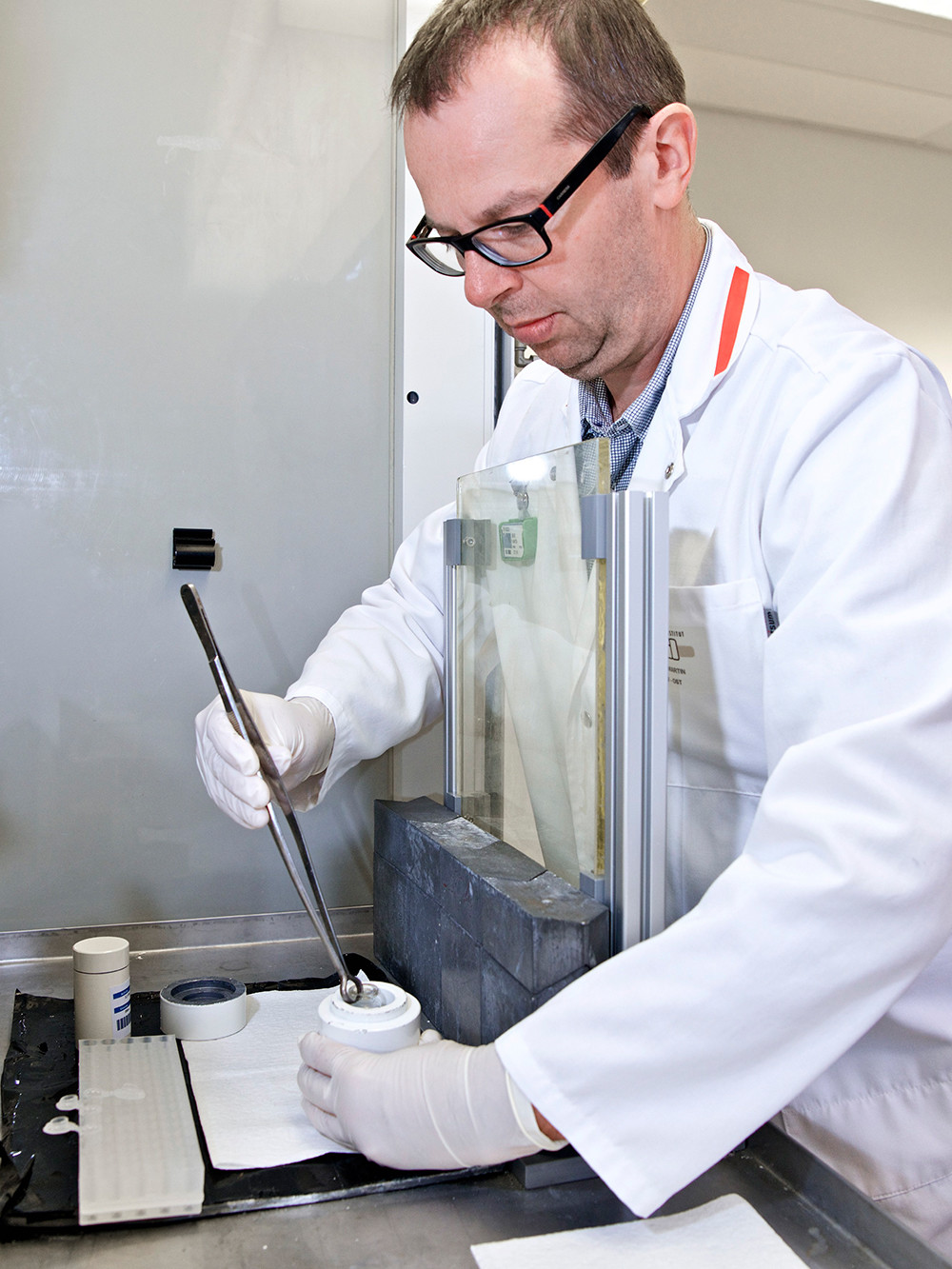 The utmost care is always called for when handling radioactive materials: Martin Béhé working behind radiation shielding glass and lead blocks as he removes the radionuclide lutetium-177 from a small lead container to couple it to a target molecule. (Photo: Paul Scherrer Institute/Markus Fischer)