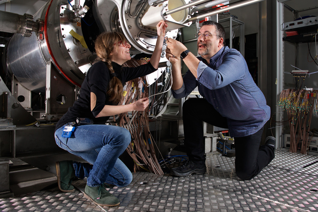 The PSI-scientists Angela Papa and Stefan Ritt at the MEG experiment. A lot of cables are necessary to read out the many particle detectors. With these, the scientists analyse all of the detected particle decays in the search for the special MEG decay. (Photo: Paul Scherrer Institute/Markus Fischer)