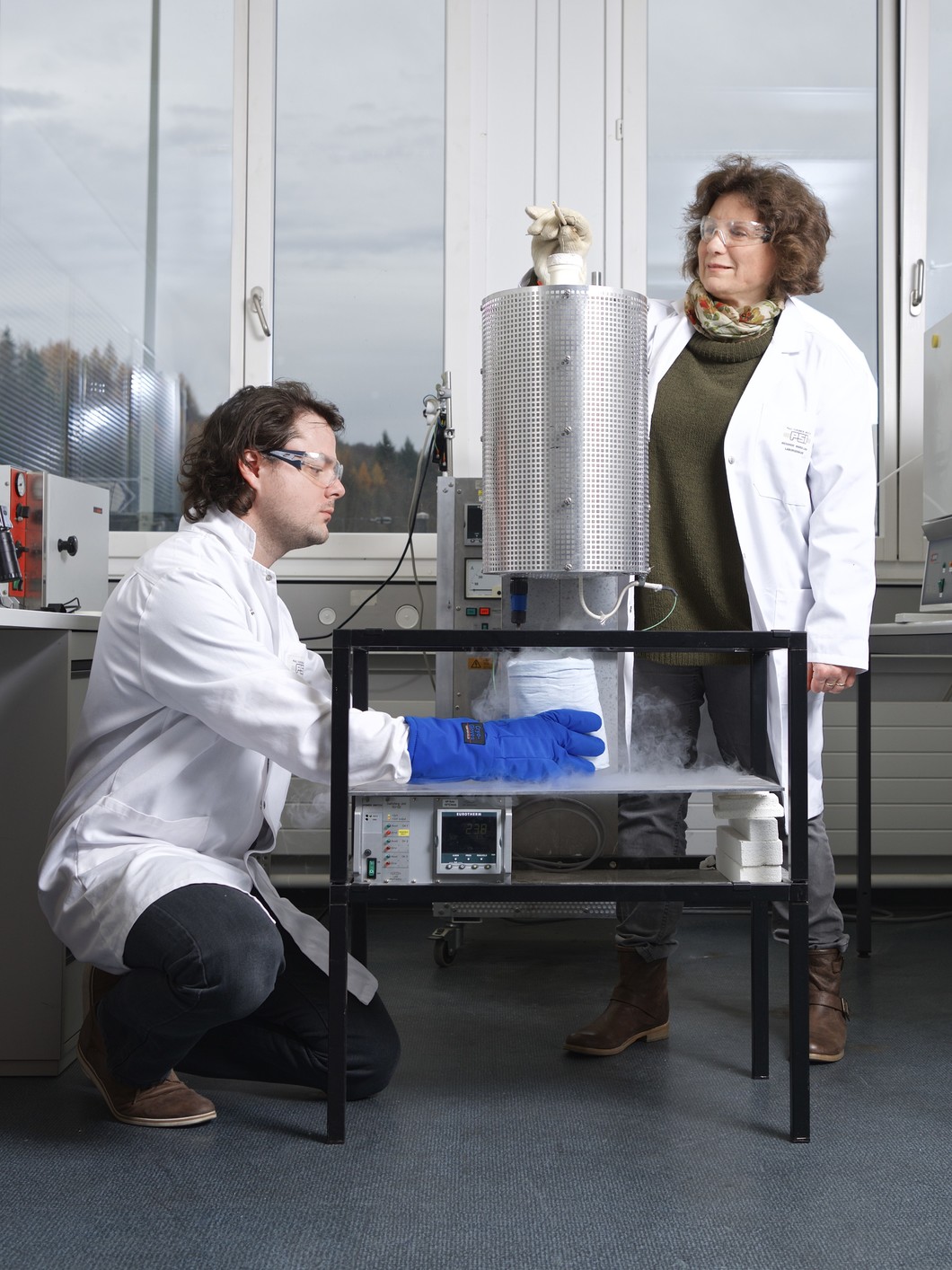 Mickaël Morin et Marisa Medarde, chercheurs au PSI, congèlent l’arrangement atomique du matériau multiferroïque YBaCuFeO5. L’échantillon de matériau est d’abord chauffé dans un four à 1000 degrés Celsius, avant d’être plongé dans un récipient rempli d’azote liquide à moins 200 degrés Celsius. (Photo: Institut Paul Scherrer/Markus Fischer)