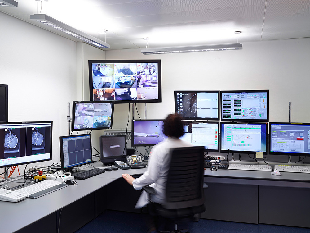 In the control room, all important information from the irradiation device Gantry 2 is displayed on several monitors. Video cameras in the treatment room transmit the current position of the device and observe the patient. This ensures that the proton therapy proceeds precisely according to the treatment plan.
(Photo: Scanderbeg Sauer Photography)