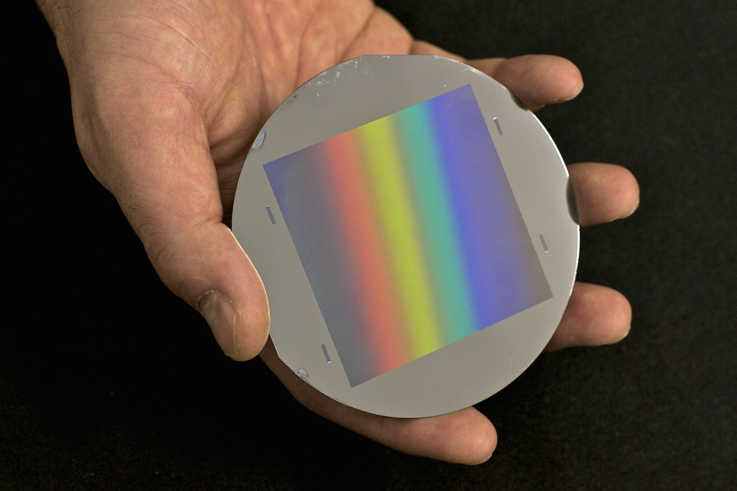 Figure 1: One of the gratings with fine lines in the micrometer range manufactured at PSI as used in the neutrons grating interferometer. The wafer has a diameter of 100 mm. The grid area is 64 x 64 mm2. The rainbow is caused by the refraction of light at the fine structures of the grating.