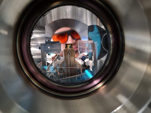 A researcher looks into the ultra-high vacuum chamber of a trapped-ion quantum computer at PSI. 