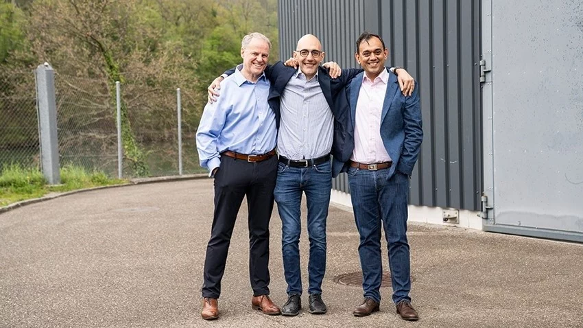 Die Mitbegründer von Metafuels Leigh Hackett (links) und Saurabh Kapoor (rechts) und der Leiter der ESI-Plattform Marco Ranocchiari (Mitte) vor der Forschungshalle auf dem PSI-Campus – hier soll die neue Pilotanlage zur Herstellung von nachhaltigem Flugtreibstoff entstehen.