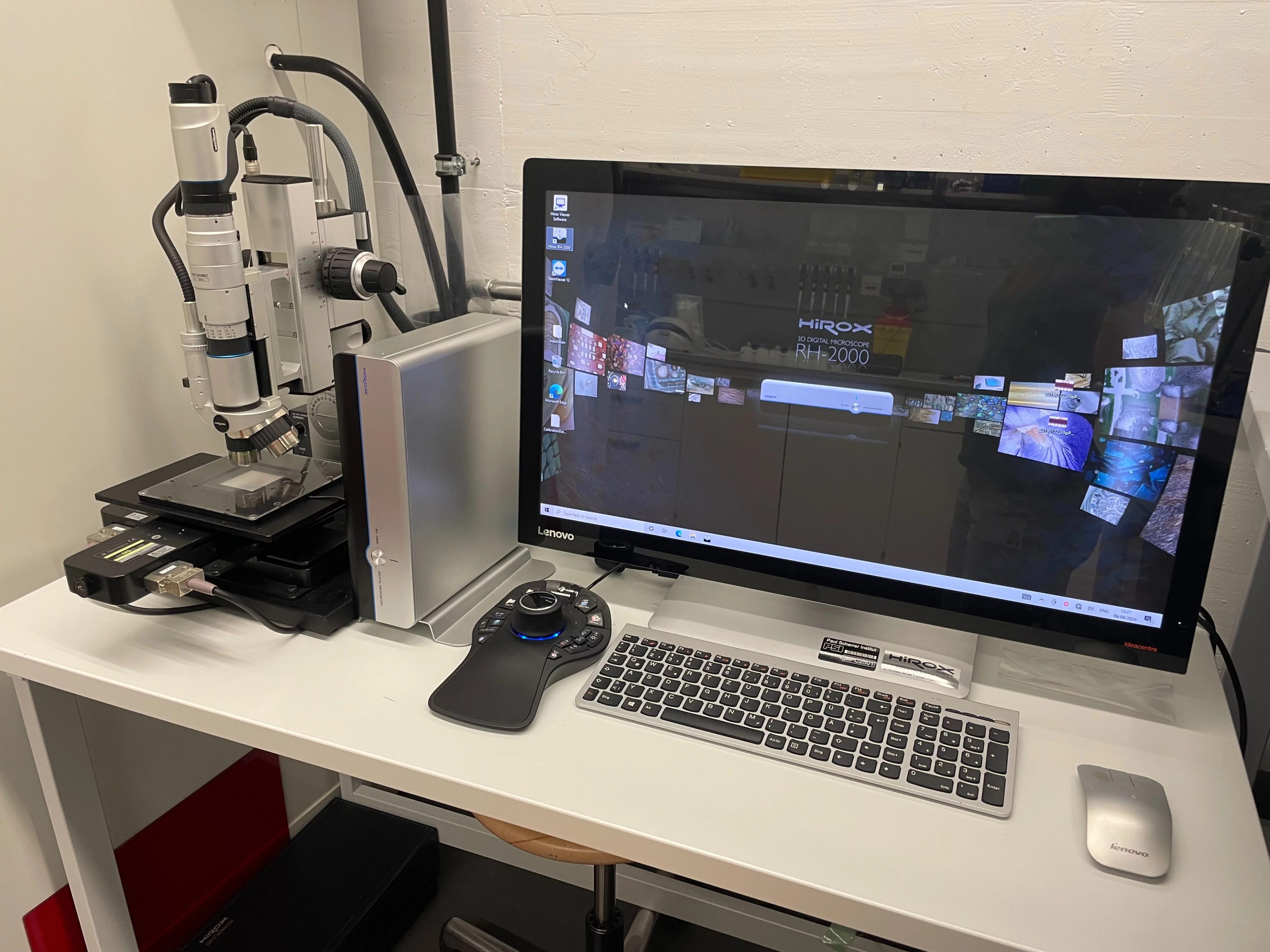 A computer screen and keyboard next to a digital microscope