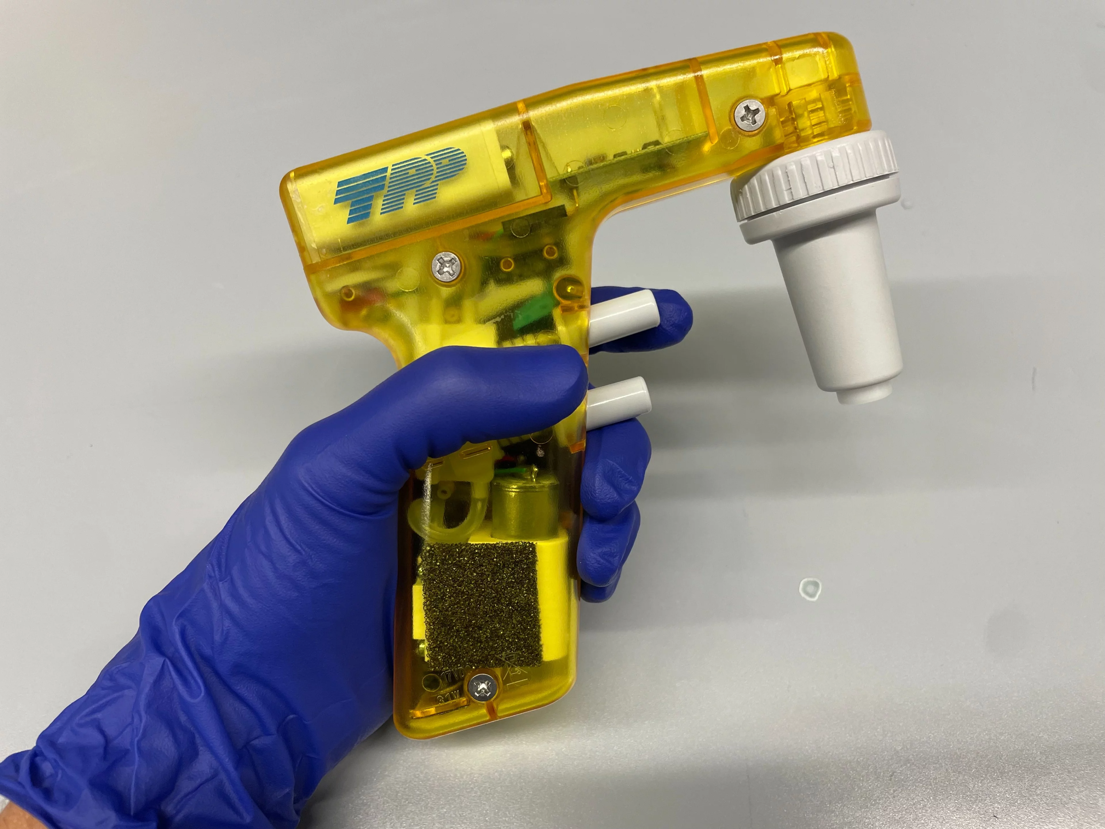 Yellow mechanical pipette held by a hand in a purple nitrile glove