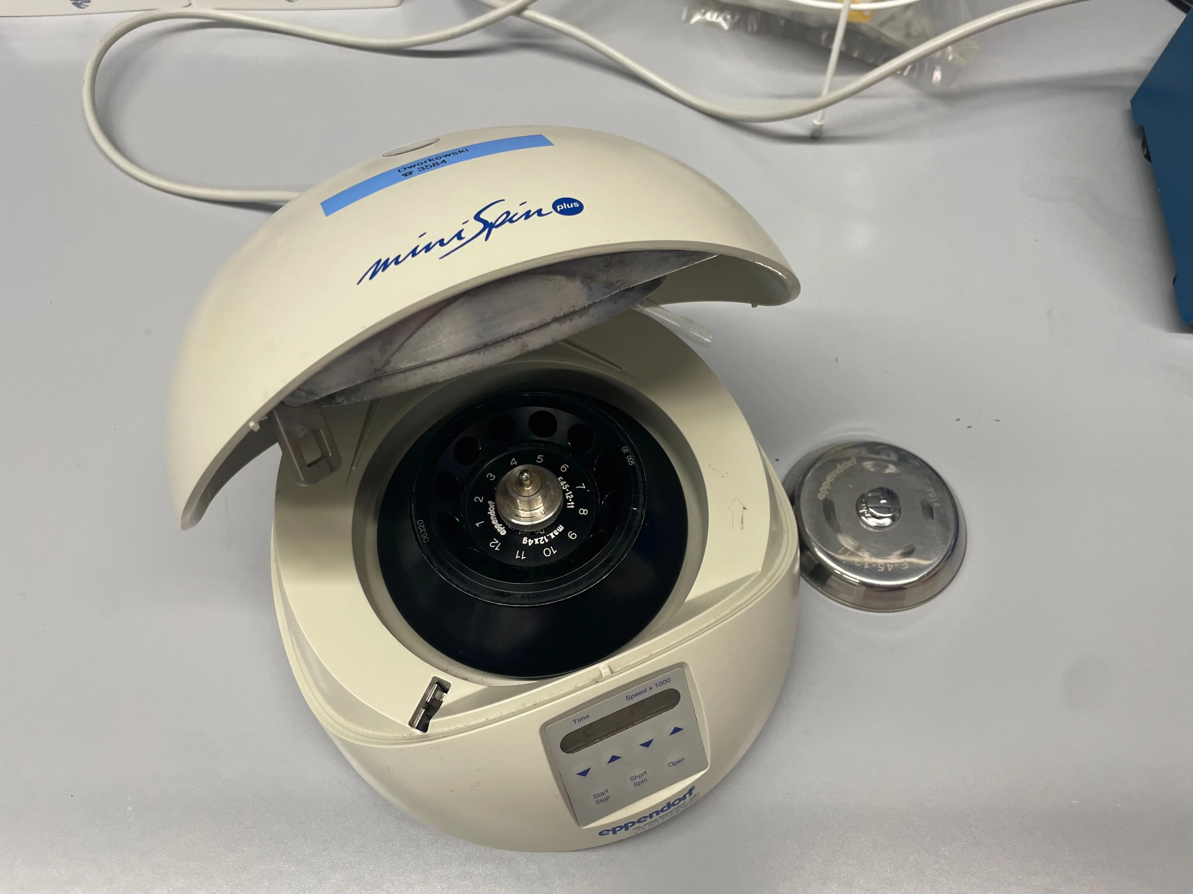 Small beige centrifuge with black rotor and metal lid