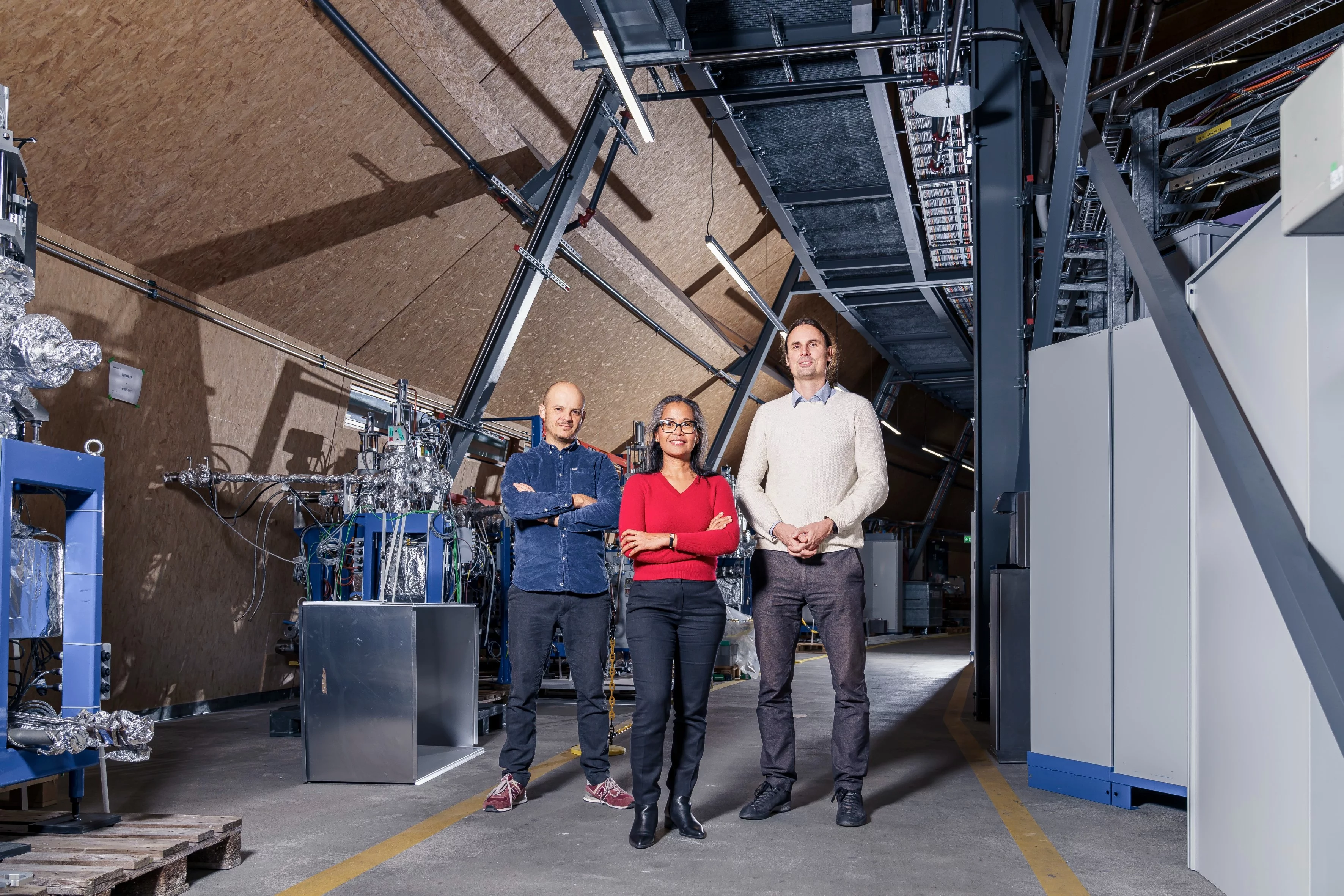 Die beiden PSI-Physiker Dario Ferreira Sanchez und Margie Olbinado mit Vlad Novak vom Technologietransferzentrum ANAXAM (von links nach rechts) in der Halle der Synchrotron Lichtquelle Schweiz SLS.
