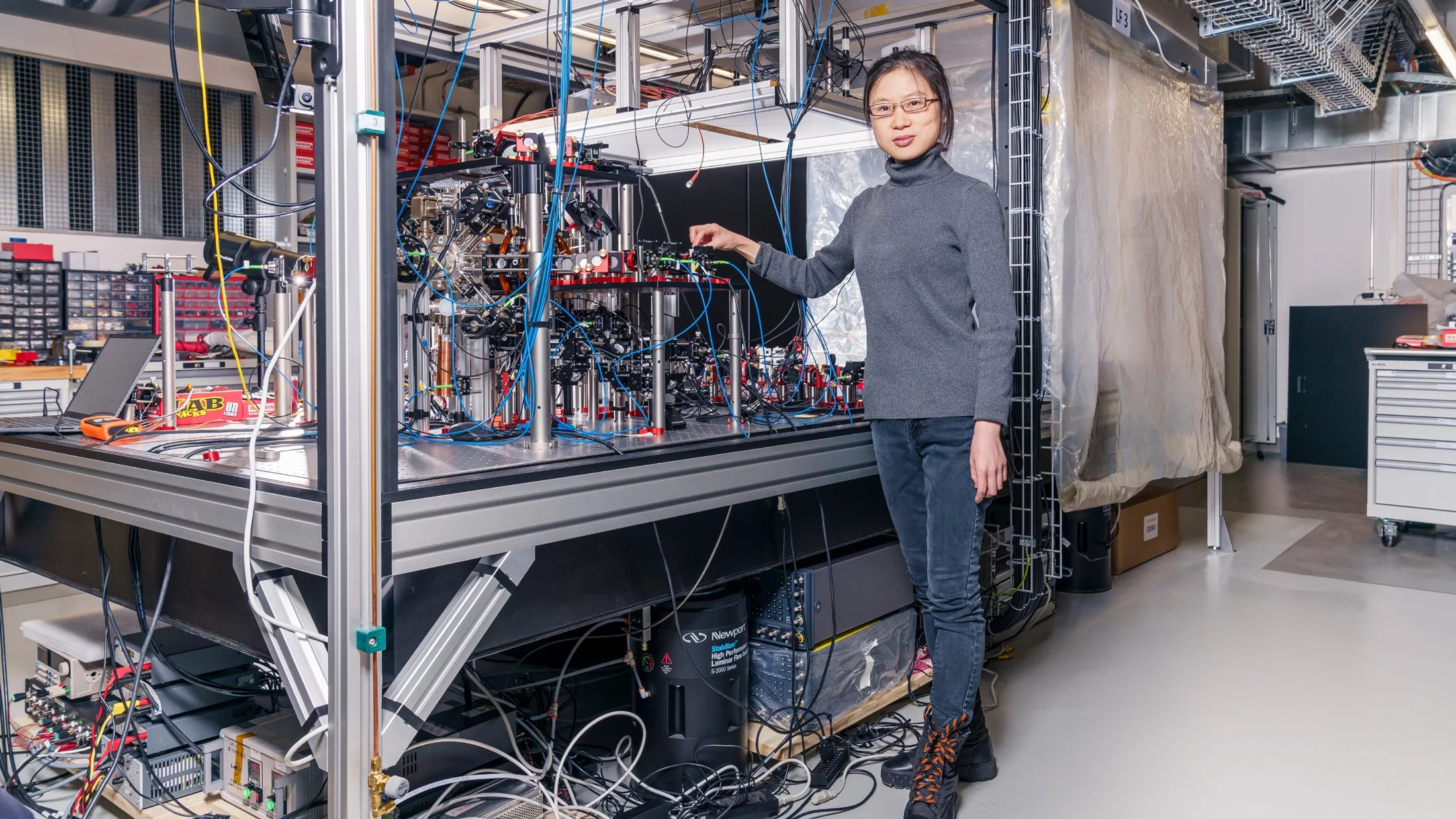Wenchao Xu by the Quantum Engineering group’s experimental setup, which uses neutral, individual atoms as building blocks for quantum computers.