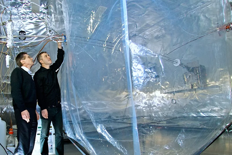 PSI scientists Urs Baltensperger (left) and André Prévôt next to the institute's smog chamber where processes going on in the atmosphere are simulated.