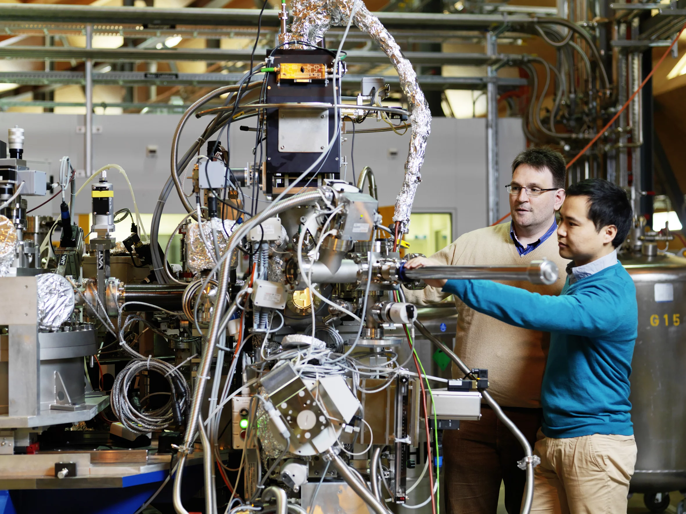 PSI scientist Thorsten Schmitt (left) and post-doc Kejin Zhou (right) at the RIXS measuring station of the ADRESS beamline at SLS, where they are inserting a sample into the measuring apparatus. Here, X-rays are used for investigating materials with very high precision. (Photo: Scanderbeg Sauer Photography)