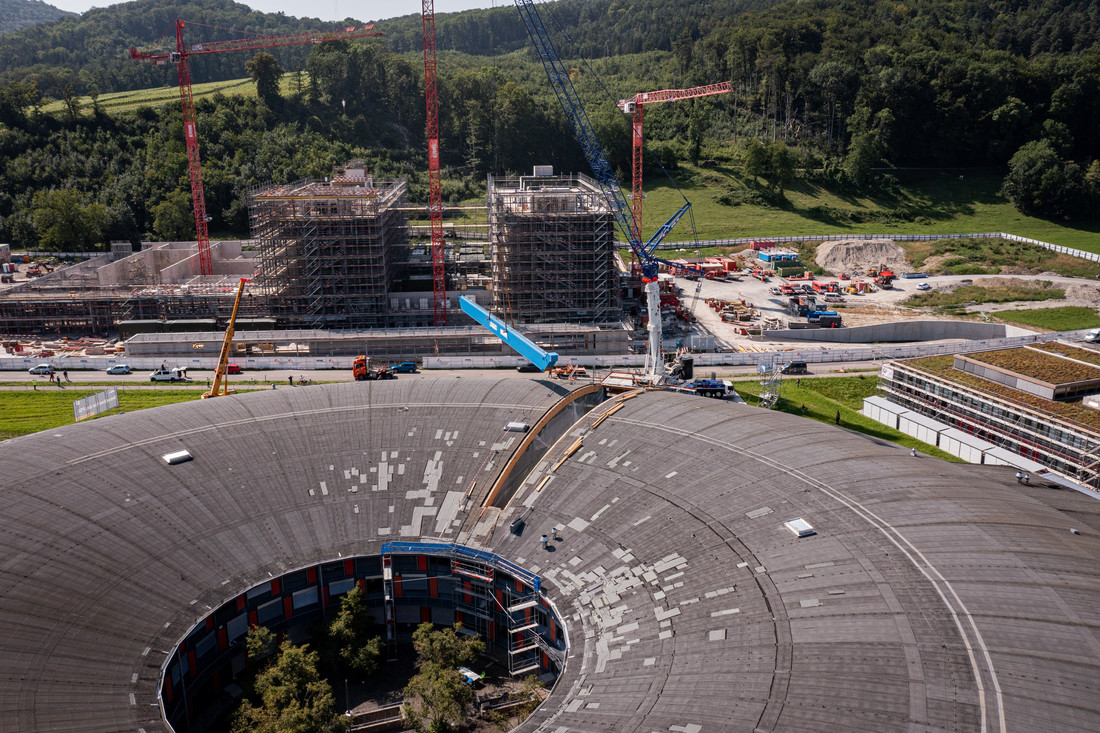 Le pont de la nouvelle grue (en bleu) en train d’être descendu par l’ouverture du toit dans le hall de la SLS. 