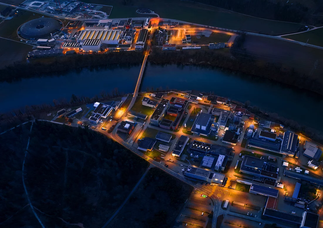 Helligkeitssensoren am PSI registrieren die heraufziehende Dämmerung und auf dem gesamten Gelände schaltet sich die Beleuchtung ein. Aus der Vogelperspektive wirkt das grösste Schweizer Forschungsinstitut mit seinen mehr als 2000 Mitarbeitenden beinahe wie eine kleine Ortschaft.