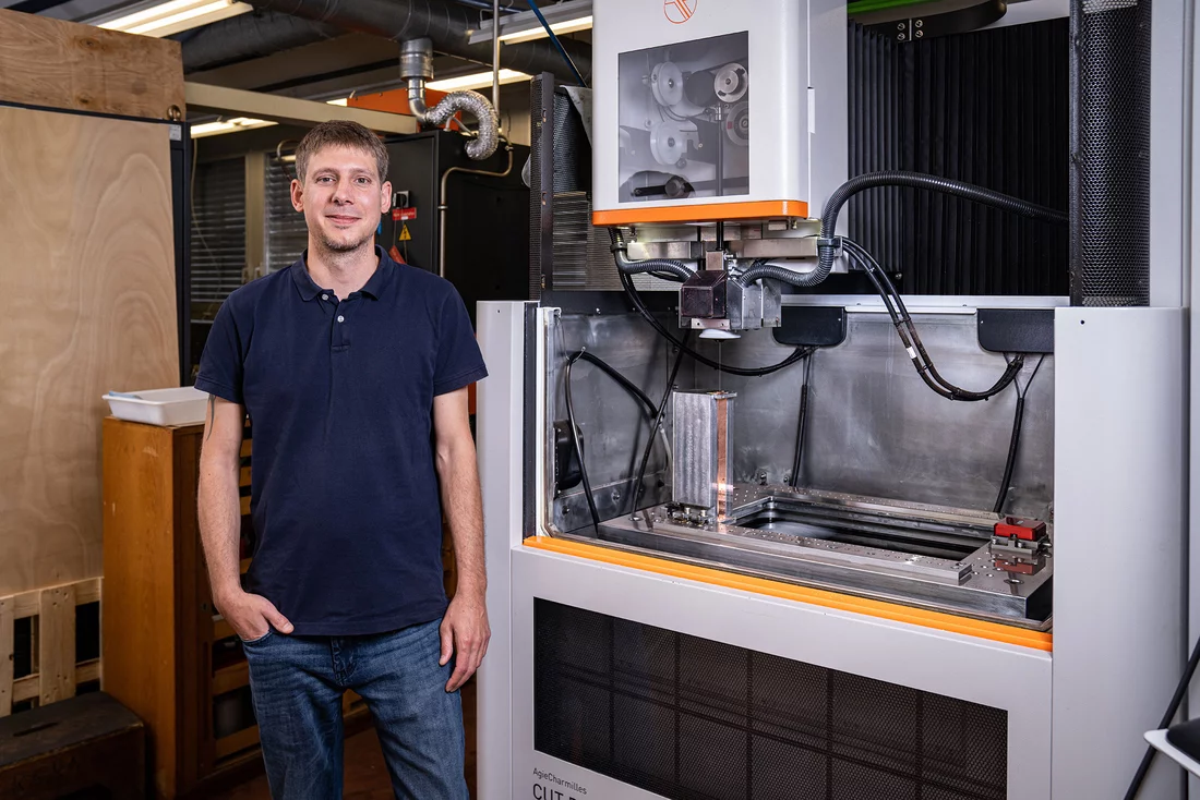 René Sieber standing next to one of the two wire-eroding machines 