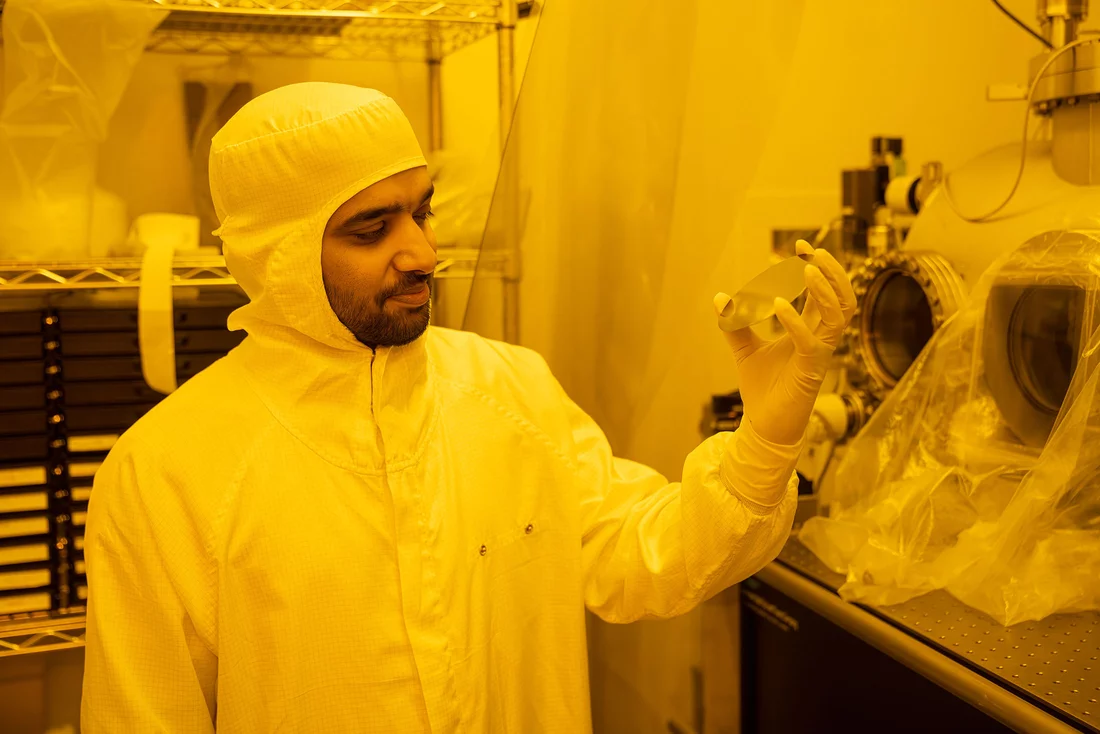 Prajith Karadan im Reinraum betrachtet die spiegelnde Oberfläche eines Wafers aus Silizium. 