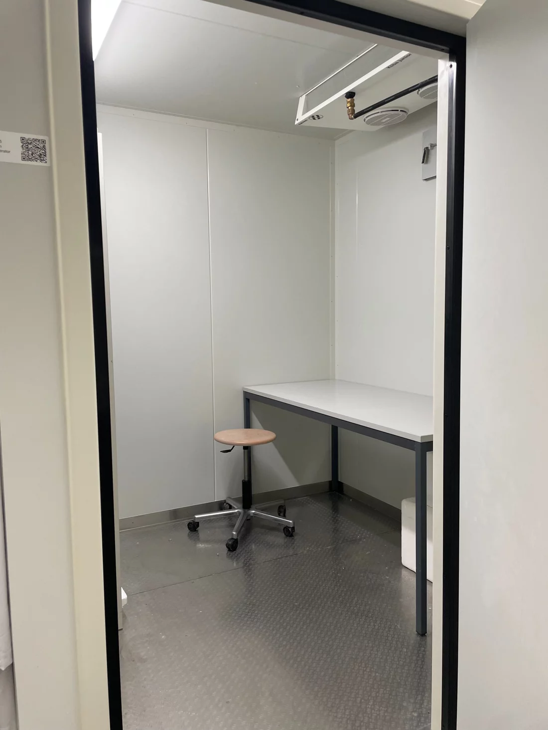 The inside of a grey cold room with a desk and chair