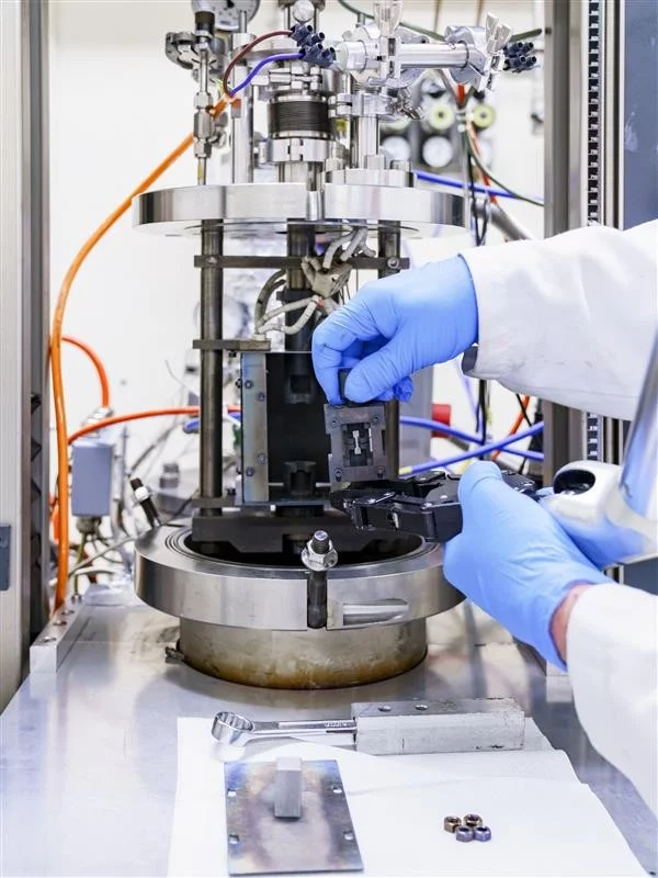 Setting up tensile testing of irradiated STIP specimens. 