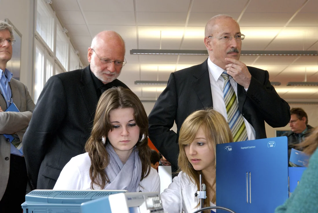 Regierungsrat Rainer Huber und PSI-Direktor Martin Jermann lassen sich das Experiment von Sian Mehser und Lea Thommen der Klasse 3a der Bezirksschule Möhlin erläutern.
