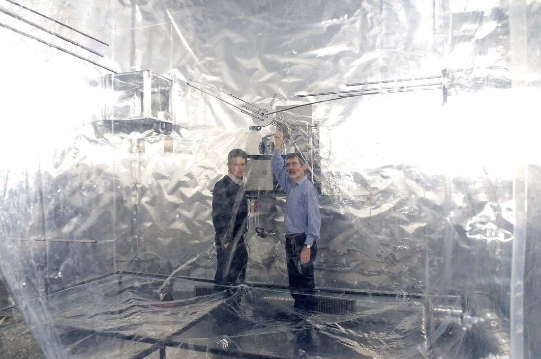 PSI scientists Urs Baltensperger (left) and Josef Dommen next to the smog chamber, where processes in the atmosphere are simulated. (PSI/F. Reiser)