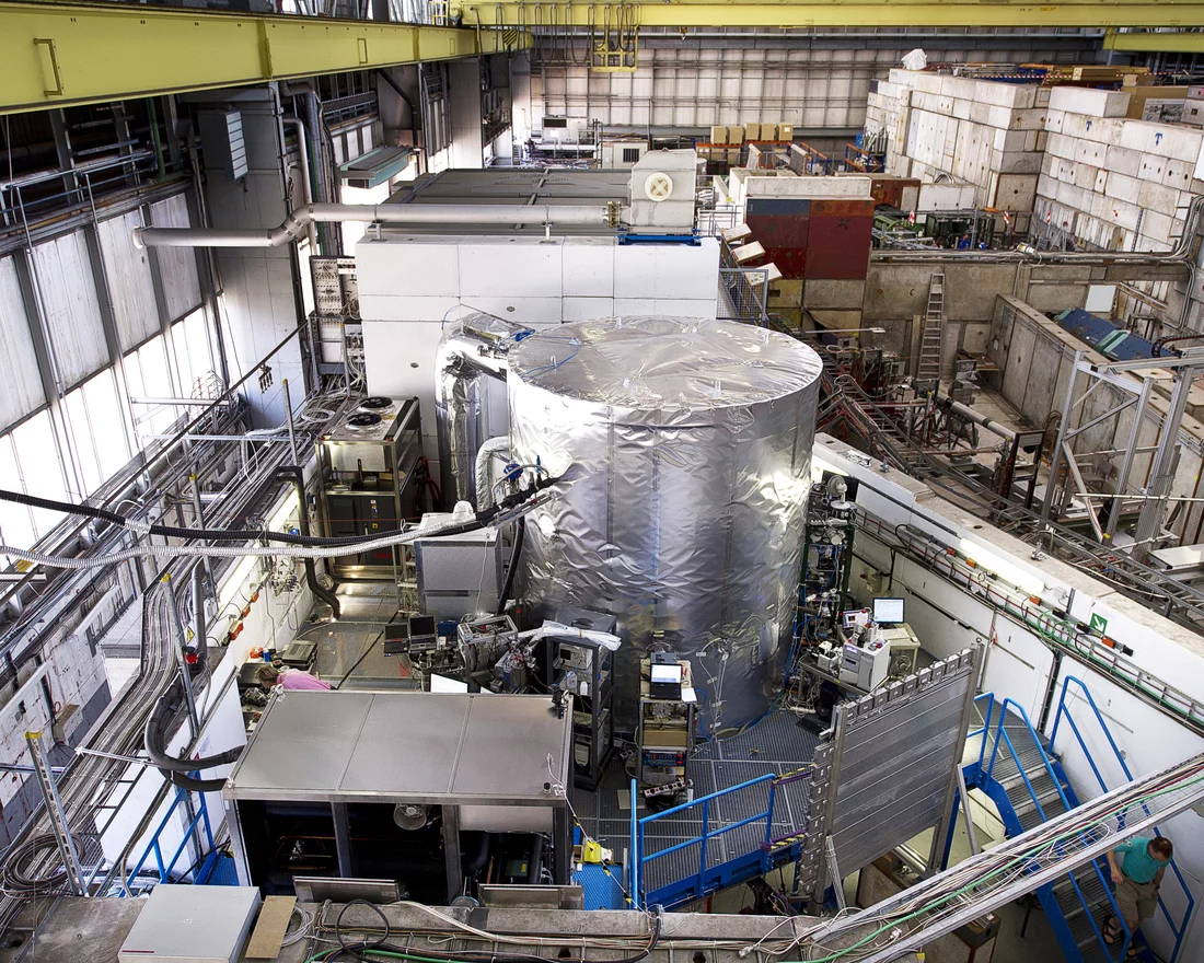 Der Zylinder ist die Temperatur-thermostatisierte CLOUD-Kammer am CERN. Hier werden Vorgänge in der Atmosphäre simuliert – ein Teilchenstrahl aus einem Teilchenbeschleuniger simuliert die kosmische Strahlung. Sternförmig um die Kammer herum sind die Messinstrumente angeordnet. Der Strahl kommt von unten ins Bild und wird, bevor er auf die Kammer trifft, mit der senkrechten 'Wandtafel' vermessen. Quelle: CERN