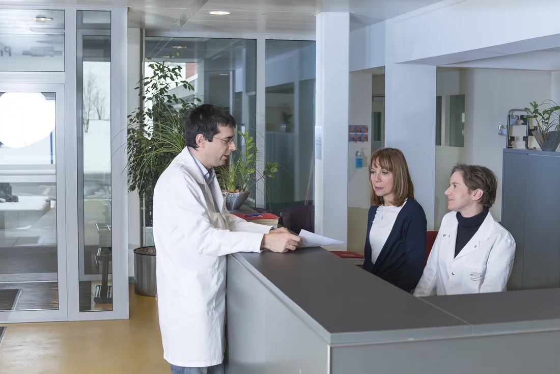 In the friendly and bright environment of the reception room of the Center for Proton Therapy, Dr. Marc Walser (left) talks to Daniela Buckenmeyer and Jolanda Dainese Meier about the next treatement dates of a patient. (Photo: Paul Scherrer Institute/Mahir Dzambegovic)