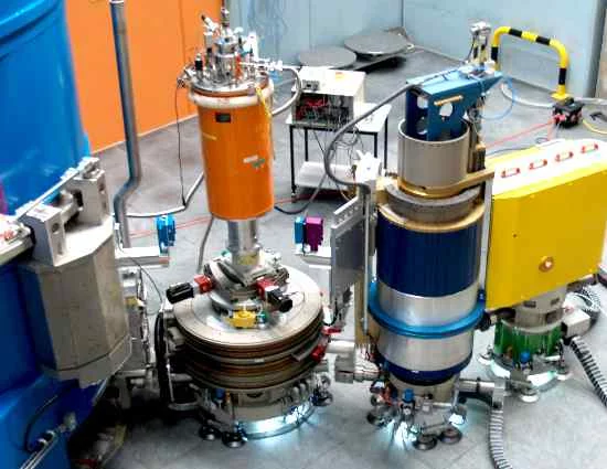 From left to right:  monochromator shielding, sample table with cryostat, analyzer shielding, detector housing