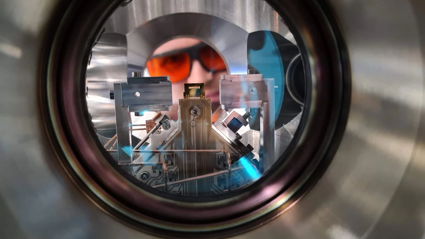 Ein Forscher blickt in die Ultrahochvakuumkammer eines Quantencomputers am PSI, der mit gefangenen Ionen arbeitet. 