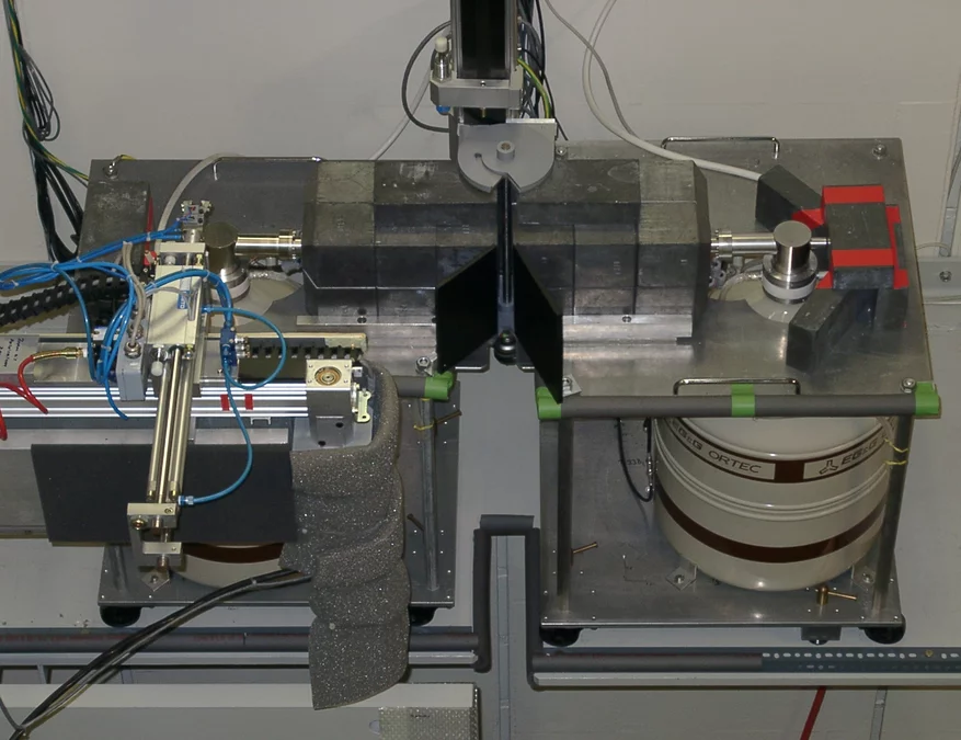 Gamma-scanner machine featuring two hyper pure germanium detectors positioned back-to-back and a rotating gripping device to move the pin axially