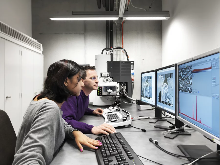 Die PSI-Forschenden Pallavi Verma (links) und Wolfgang Märkle untersuchen Lithium-Ionen-Batterien mit Hilfe eines Rasterelektronenmikroskops (Foto: Scanderbeg Sauer Photography)