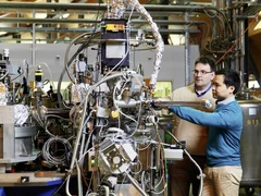 PSI scientist Thorsten Schmitt (left) and post-doc Kejin Zhou (right) at the RIXS measuring station of the ADRESS beamline at SLS, where they are inserting a sample into the measuring apparatus. Here, X-rays are used for investigating materials with very high precision. (Photo: Scanderbeg Sauer Photography)