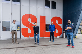 Mirko Holler, Zirui Gao, Johannes Ihli et Manuel Guizar-Sicairos (de gauche à droite), chercheurs au PSI, avec à l’arrière-plan la Source de Lumière Suisse SLS où les mesures ont été conduites.