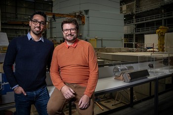Eric Ricardo Carreon Ruiz (links) und Pierre Boillat vor einem Teil der Schweizer Spallations-Neutronenquelle SINQ des PSI. 