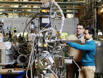 PSI researchers inserting a sample into a measuring apparatus at the SLS. Here, X-rays are used for investigating materials with very high precision.