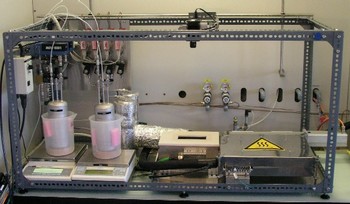 Lab setup of channel reactor with the feed system (left side of picture), channel reactor (in the middle of the picture), heating box for sampling capillary (right side of picture) and the infrared camera (top section of the picture)