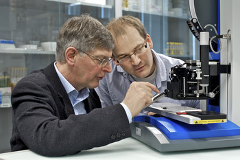 PSI researchers Gebhard Schertler and Jörg Standfuss adjusting a “robot” that can produce protein crystals needed for the determination of protein structures. (Photo: PSI/M.Fischer)