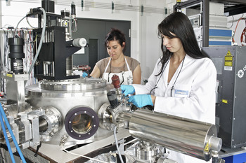 The researchers Claudia Cancellieri (left) and Mathilde Reinle-Schmitt at an apparatus that produces thin layers of different materials with the aid of a laser (Paul Scherrer Institute/M. Fischer)