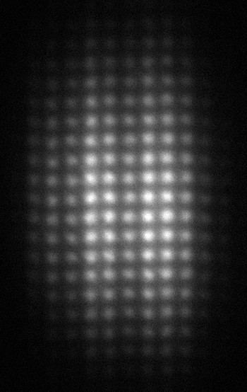 Moiré enregistré par la caméra pour une seule impulsion de rayons X. Il résulte de la superposition de la radiation déviée par le réseau de phase avec le réseau d'absorption. Par une analyse des distortions, les propriétés du miroir et la position du point de source de la lumière peuvent être déterminées.