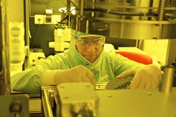 Konrad Vogelsang removes a silicon wafer with imprinted nanostructures from the thermal imprint machine. Because the process is highly susceptible to dirt particles, the technicians wear a protective suit and gloves while working in the cleanroom. (Photo: Paul Scherrer Institute/Markus Fischer)