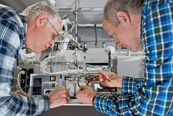 The researchers Oliver Kröcher and Martin Elsener removing a soot sample from a test tube. Picture: Paul Scherrer Institute / Markus Fischer.
