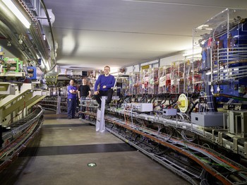 In SLS’s accelerator tunnel. The storage ring’s tube with many magnets is visible on the right. In the foreground: Andreas Lüdeke, operations manager of the SLS. (Photo: Scanderbeg Sauer Photography)