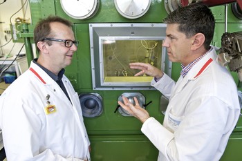Roger Schibli (right), Head of the Centre for Radiopharmaceutical Sciences, discussing the test set-up for the radio-labelling of a new drug with Martin Béhé from the Pharmacology group. In the background, a lead-clad room, where the researchers at PSI produce and process radioactive nuclides. (Photo: Paul Scherrer Institute/Markus Fischer)
