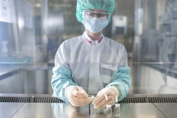 Weder Staub noch Keime sind im Reinraum erlaubt. Daher arbeitet die Pharmazeutin Susanne Geistlich mit sterilen Handschuhen und Armstulpen an einer sterilen Arbeitsbank, während sie die nichtradioaktiven Ausgangsstoffe für die Synthese eines Arzneimittels vorbereitet. (Foto:  Paul Scherrer Institut/Mahir Dzambegovic)