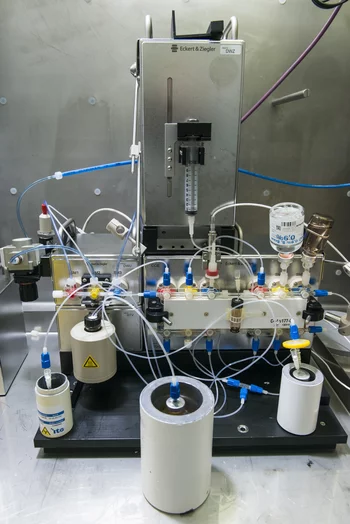 Blick in das Innere einer heissen Zelle, in der ein Syntheseapparat für radioaktive Arzneimittel steht. Die Gläschen mit dem radioaktiven Ausgangsstoff sowie dem Produkt und dem Abfall der Synthese befinden sich aus Strahlenschutzgründen in Bleibehältern. (Foto:  Paul Scherrer Institut/Mahir Dzambegovic)