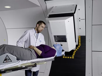 Un assistant médicotechnique prépare la patiente pour l'irradiation avec des protons à la Gantry 2 de l'Institut Paul Scherrer. La tête de la patiente est fixée par un masque spécial, ce qui permet d'être sûr que le faisceau de protons atteint précisément la tumeur. (Photo: Scanderbeg Sauer Photography)